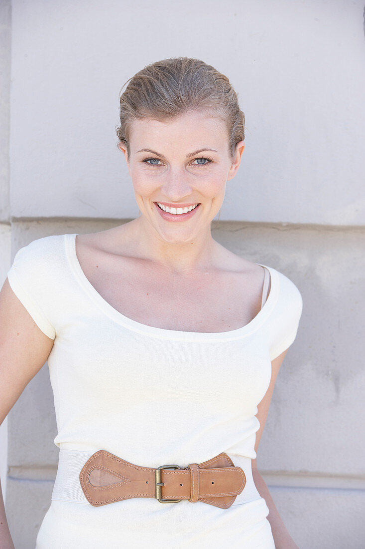 A blonde woman wearing a white shirt with a belt