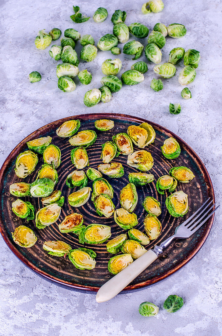 Baked Brussels sprouts on a plate and fresh Brussels sprouts