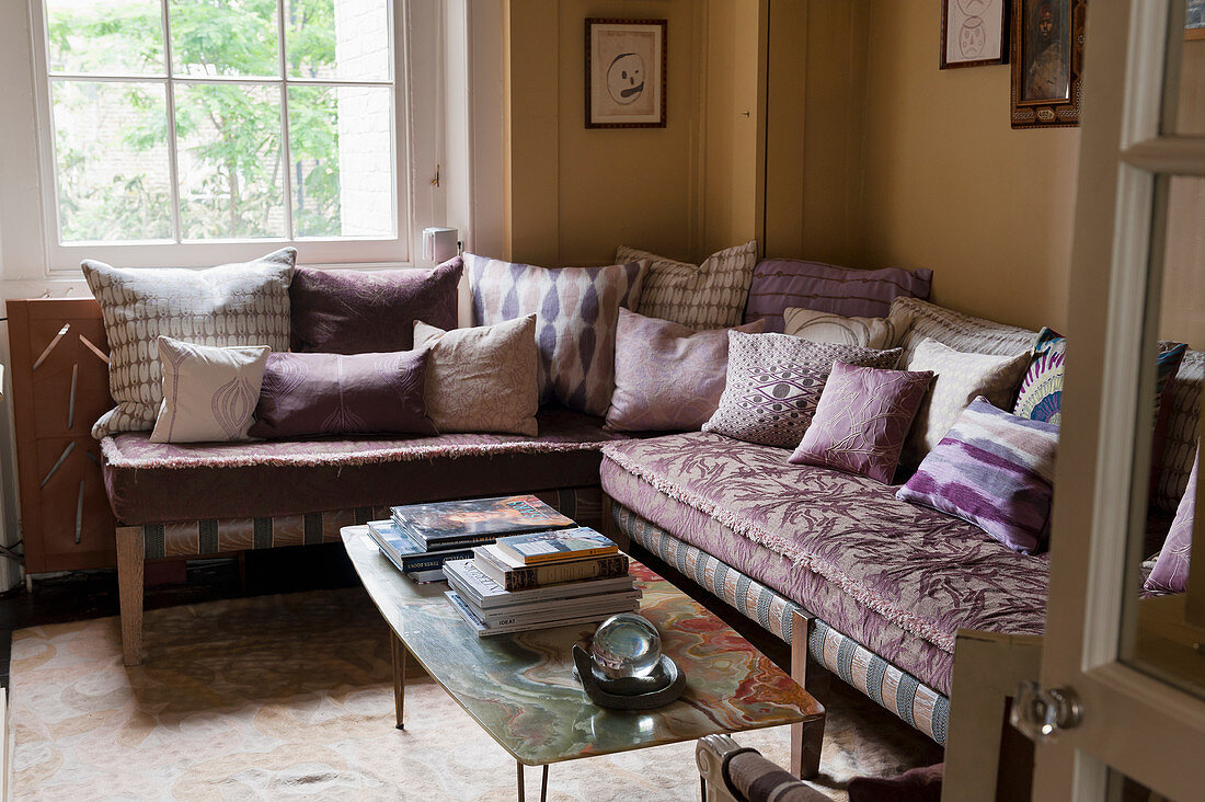 L-shaped, dusky pink velvet sofa with various scatter cushions