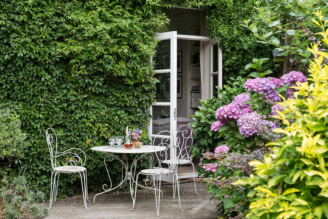 Idyllic seating area on terrace next to climber-covered façade