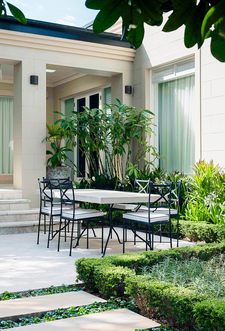 View from the garden onto the terrace with table and chairs