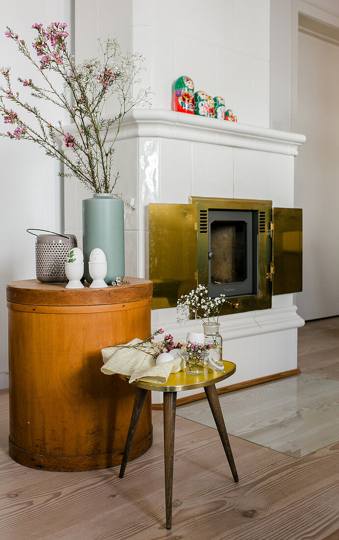 Easter decorations on stool and side table next to tiled stove