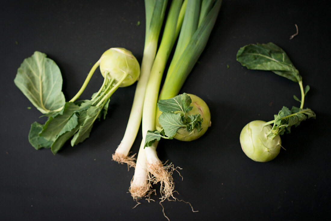 Kohlrabi and leeks on a black background