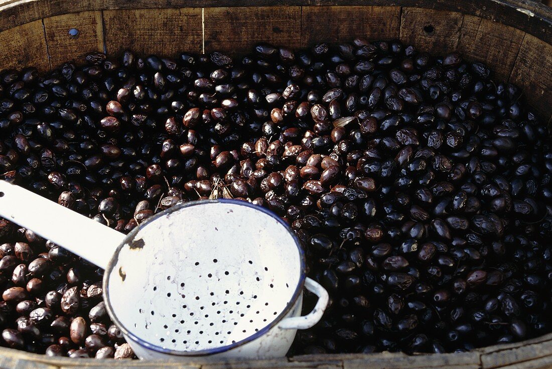 A Barrel of Pickled Olives with a Metal Scoop