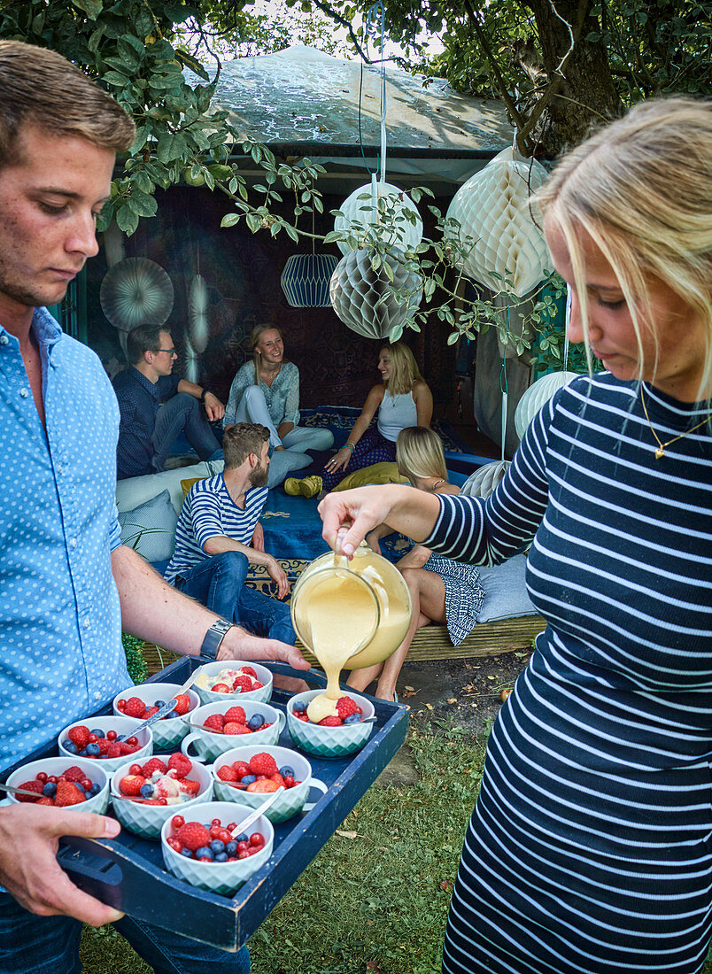 Frau gießt eiskalte Zabaione über frische Beeren