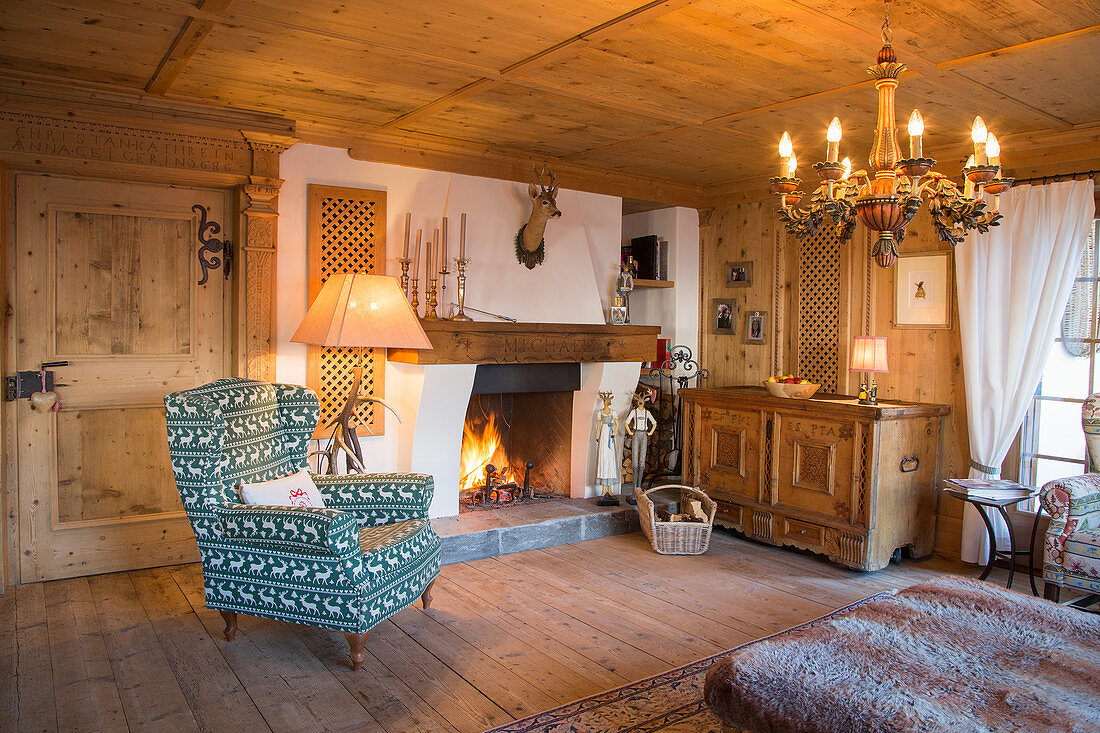 Armlehnsessel und Holztruhe neben Kamin in traditionellem Bauernhaus