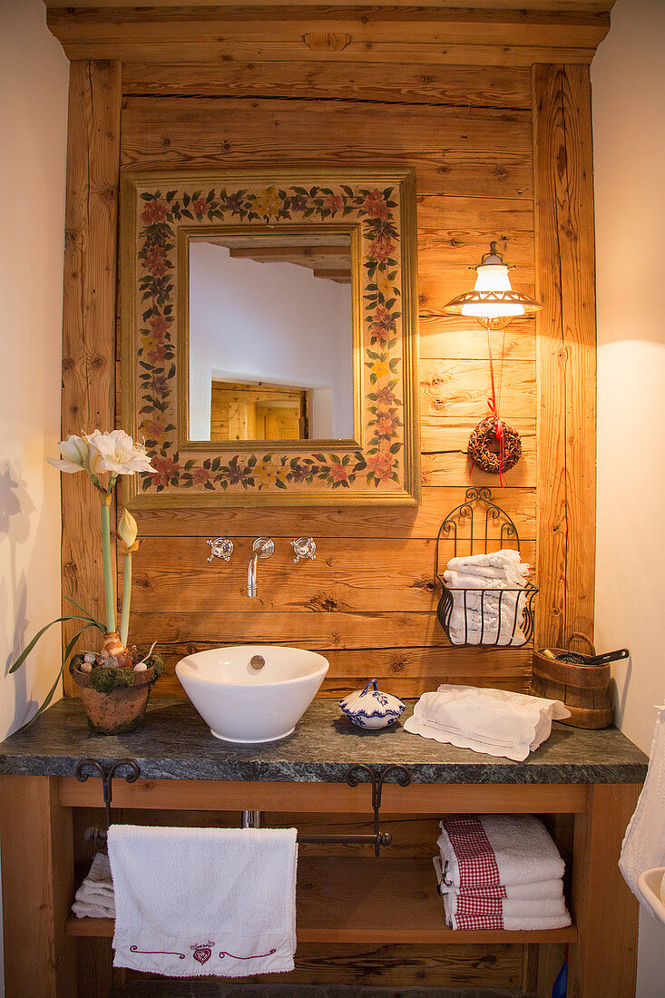 Waschtisch mit Spiegel vor Holzwand in Bauernhaus