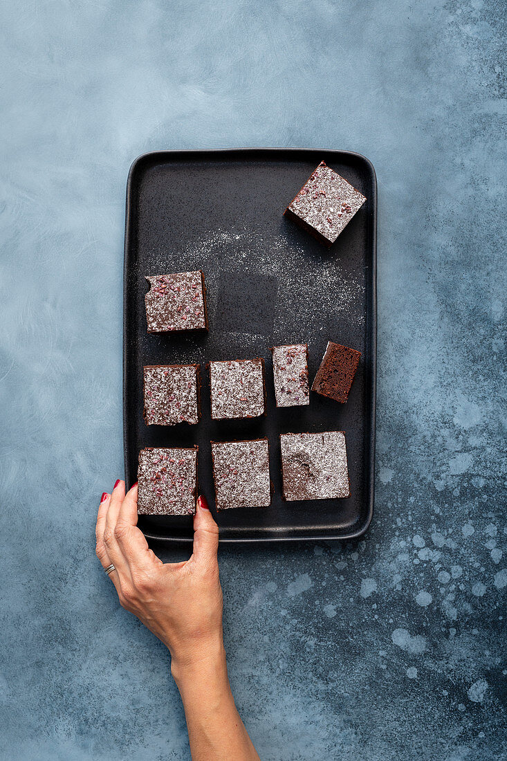 Frauenhand greift nach veganen Brownies