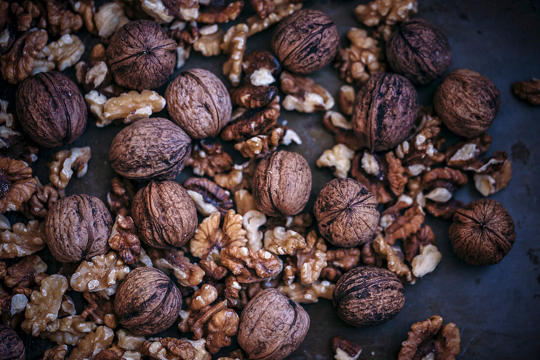 Mix of walnuts in shell and without shell on a black background