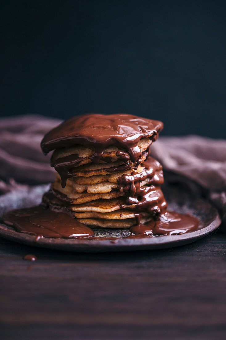Stack of banana pancakes drizzled with melted chocolate