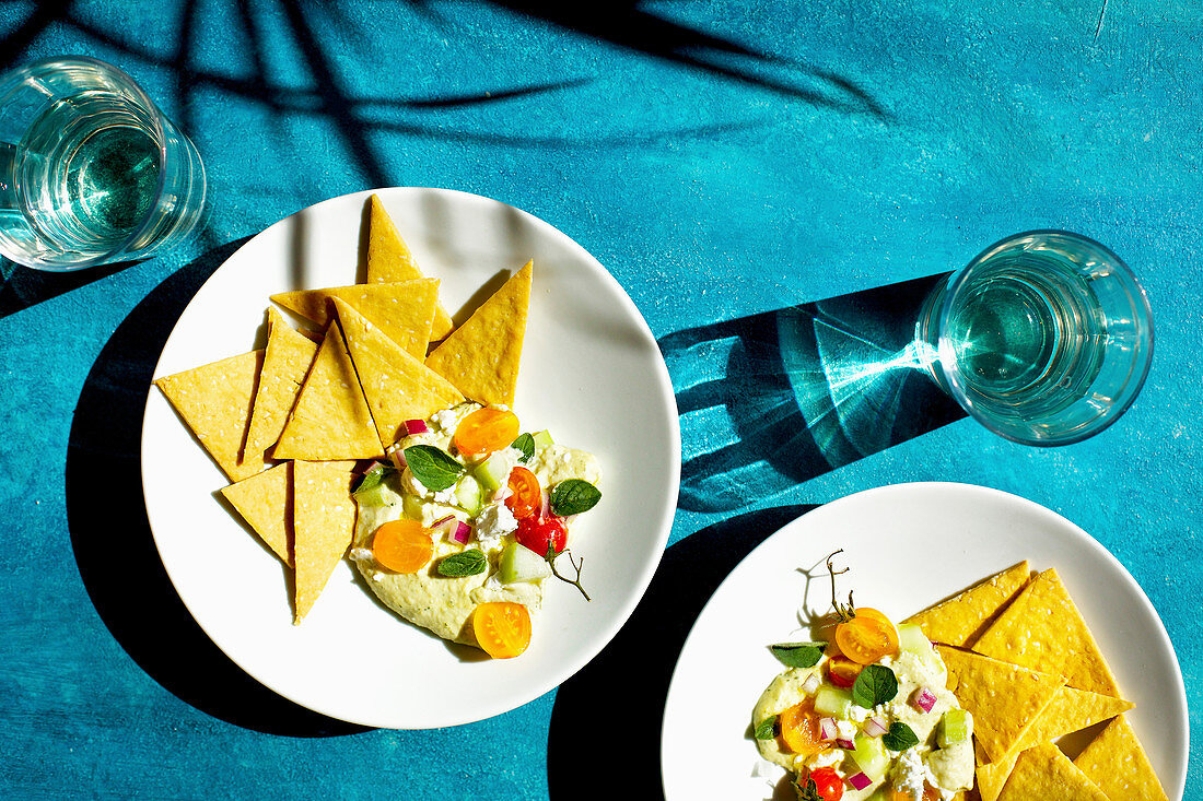 Oregano hummus with feta served with crackers on a blue background