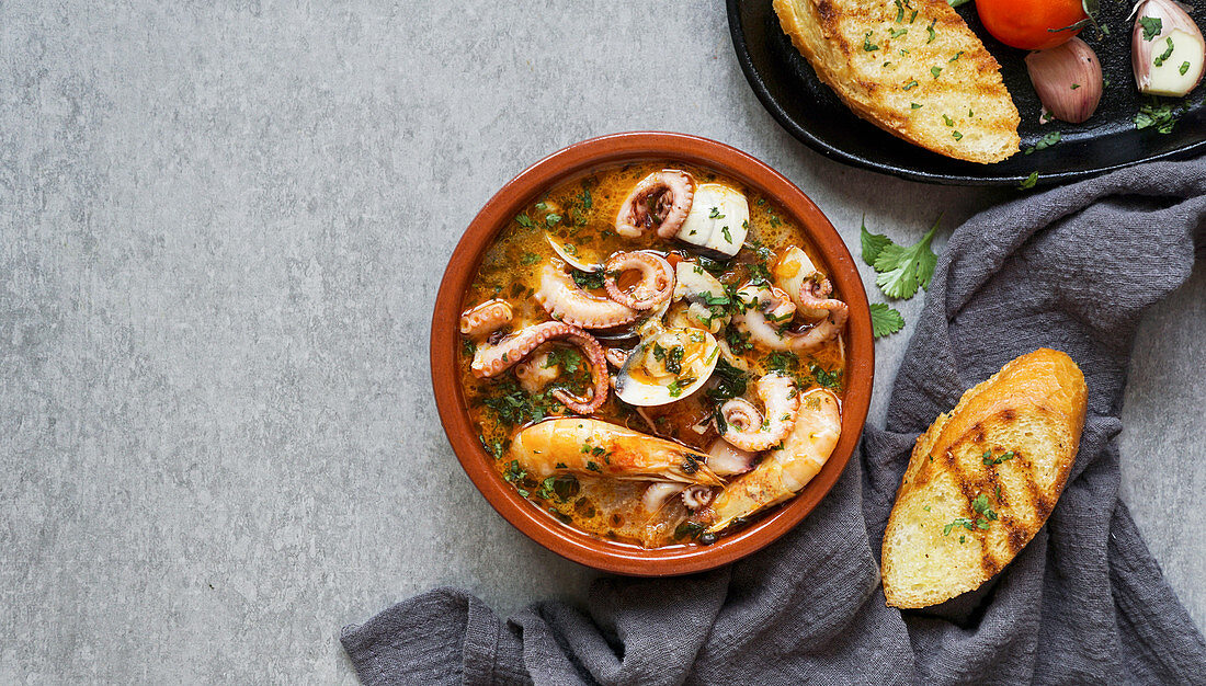 Soup of octopus and shrimps near toasts and spoon