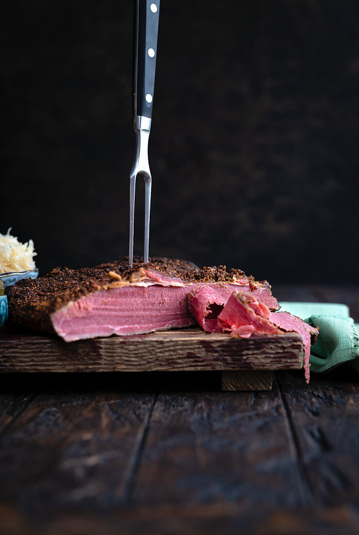 Pastrami auf Schneidebrett mit Fleischgabel