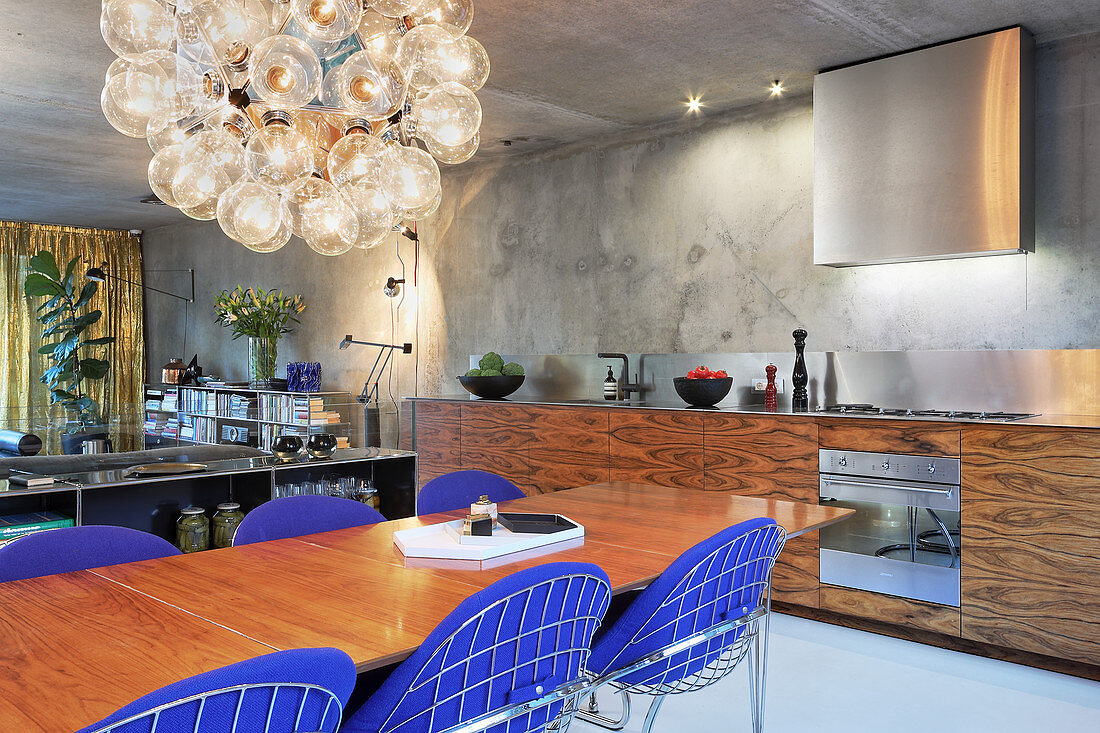 Blue designer chairs around dining table in modern, open-plan kitchen-dining room