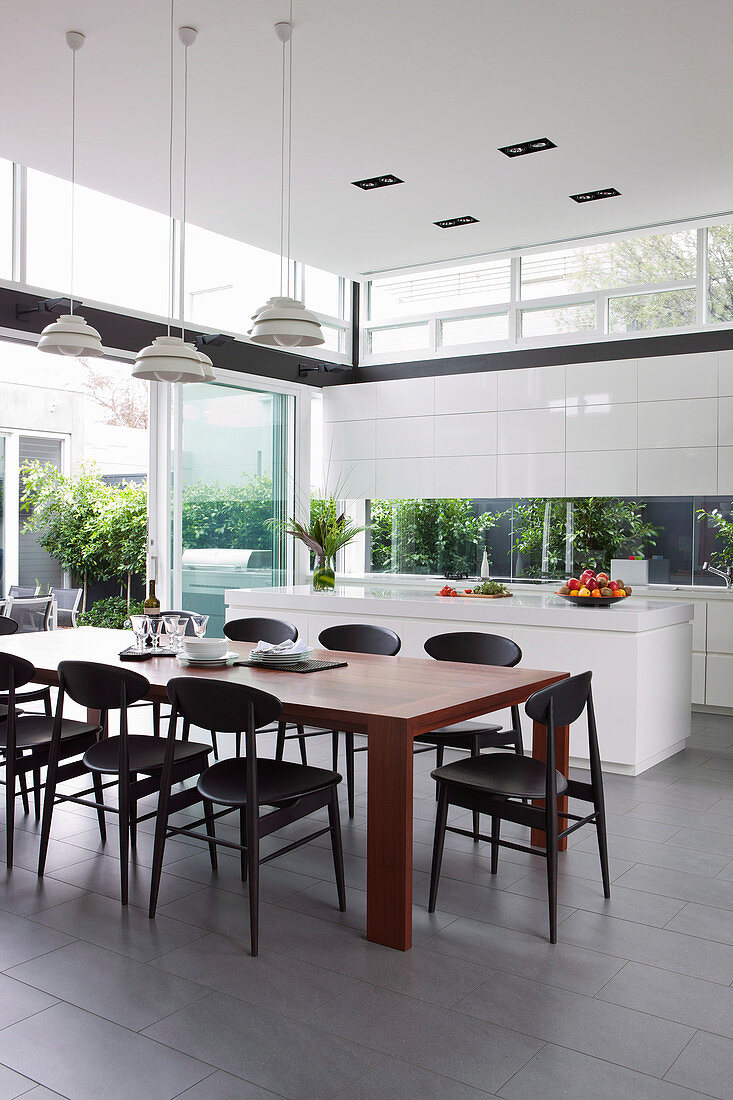 Wooden table with black chairs in front of an open kitchen in the architect's house