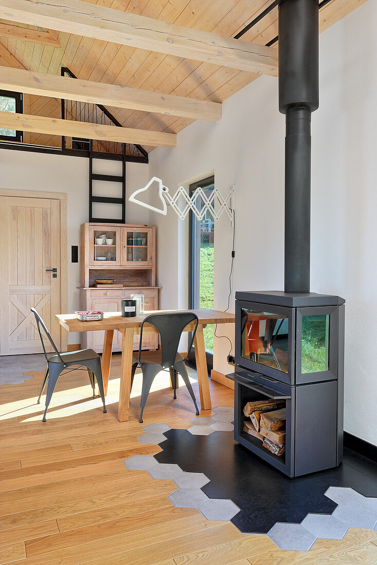 Log-burning stove and dining table in open-plan interior of converted barn