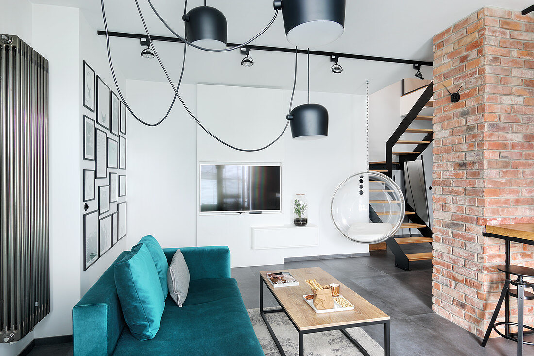 Velvet sofa, plexiglas hanging chair and exposed brickwork in open-plan interior
