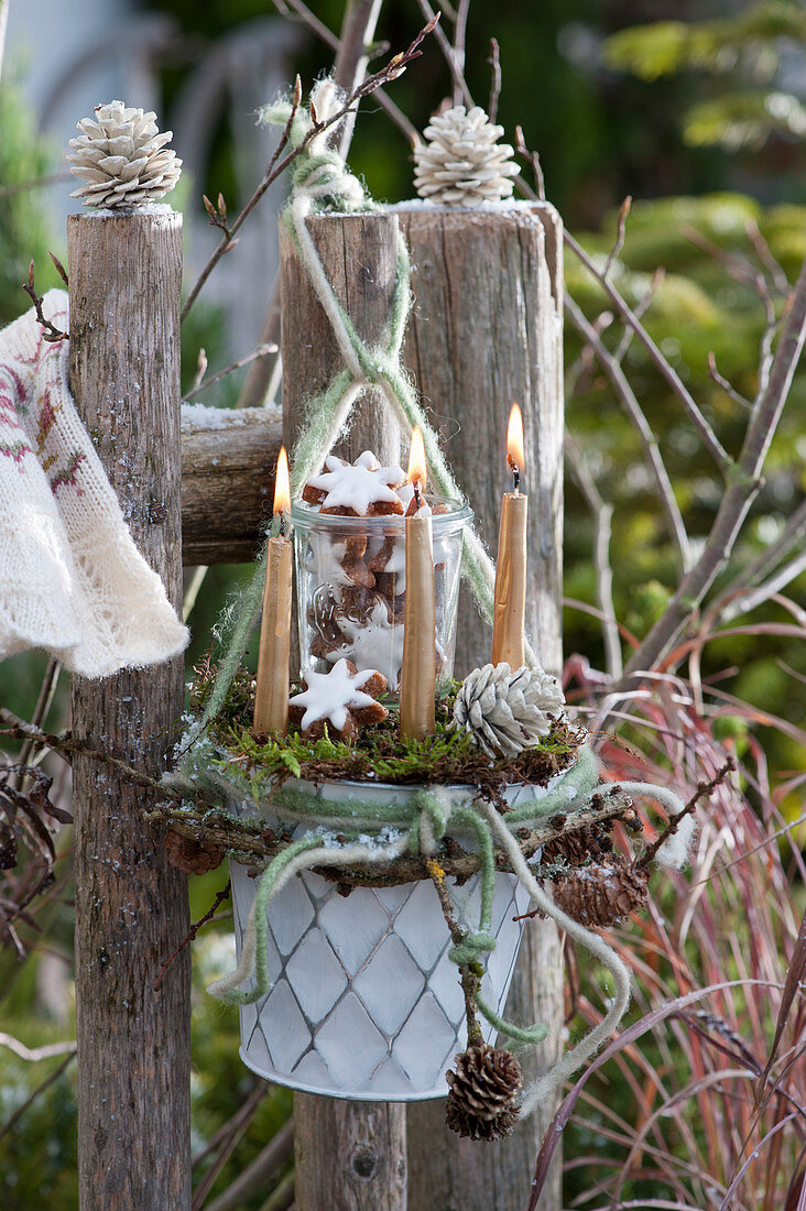 Weihnachtliche Dekoration mit Kerzen und Zimtsternen am Gartenzaun