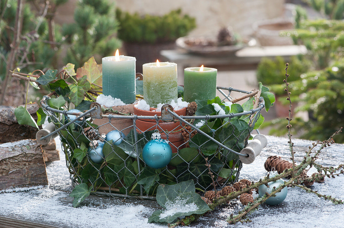 Wire basket with candles, ornaments, and ivy as a Christmas decoration