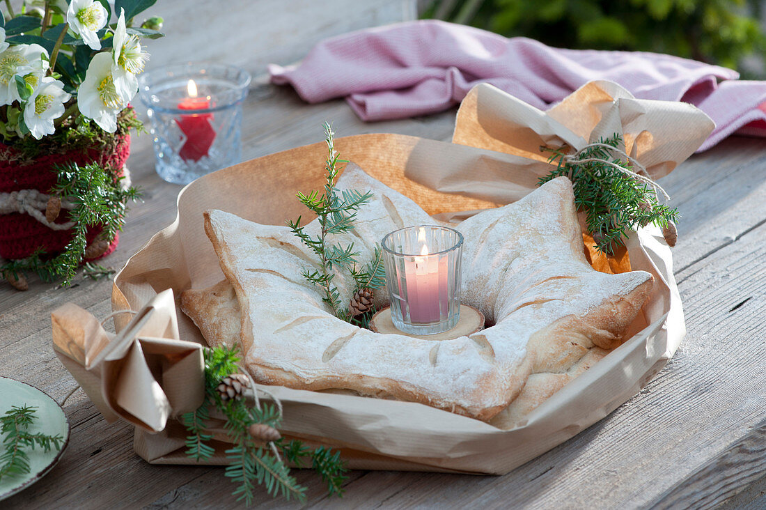 Sternförmiges Brot mit Kerze und Zweigen von Hemlocktanne