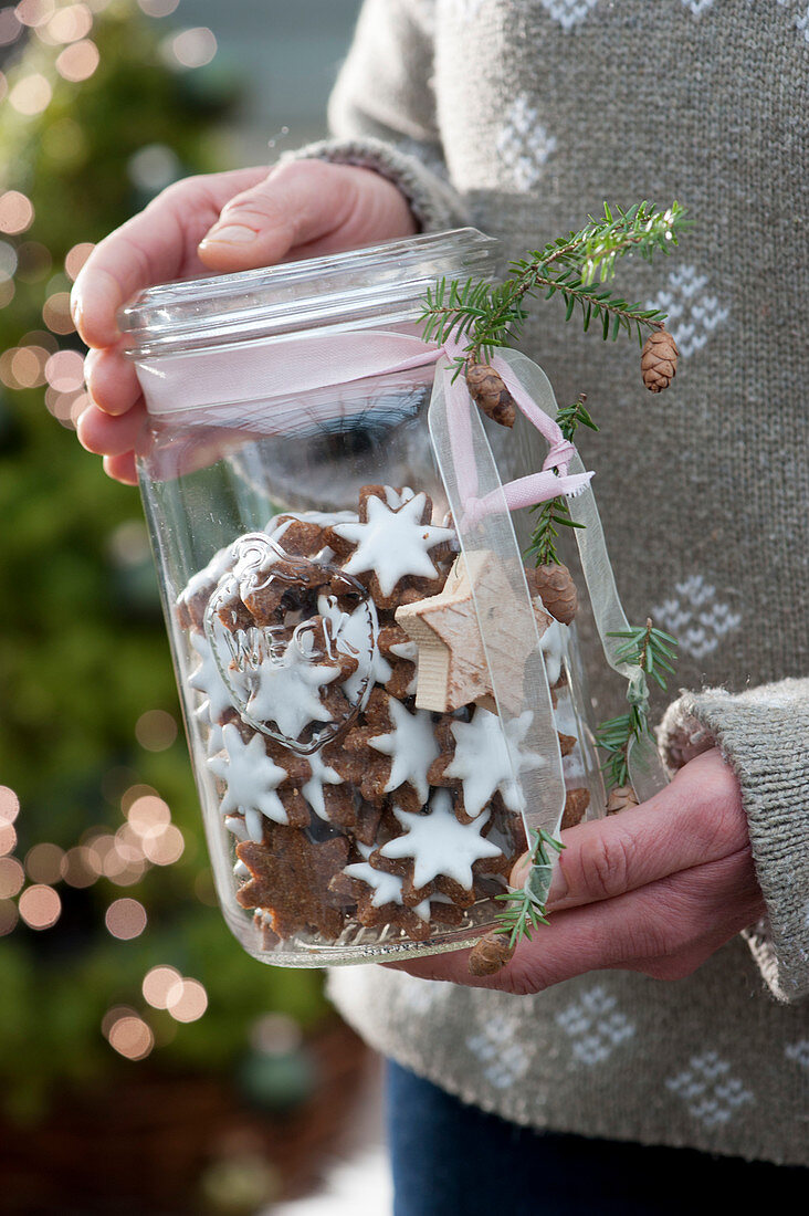 A woman holds glass with cinnamon stars