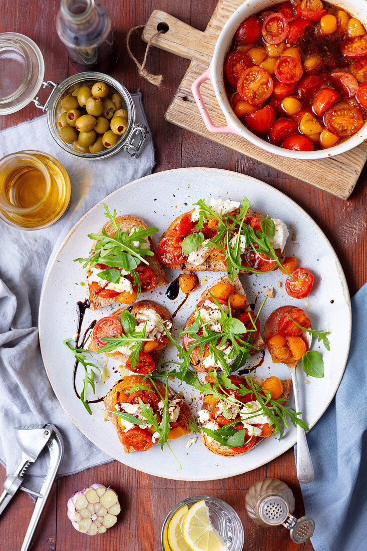 Geröstetes Brot mit gebackenen Tomaten, Mozzarella und Rucola