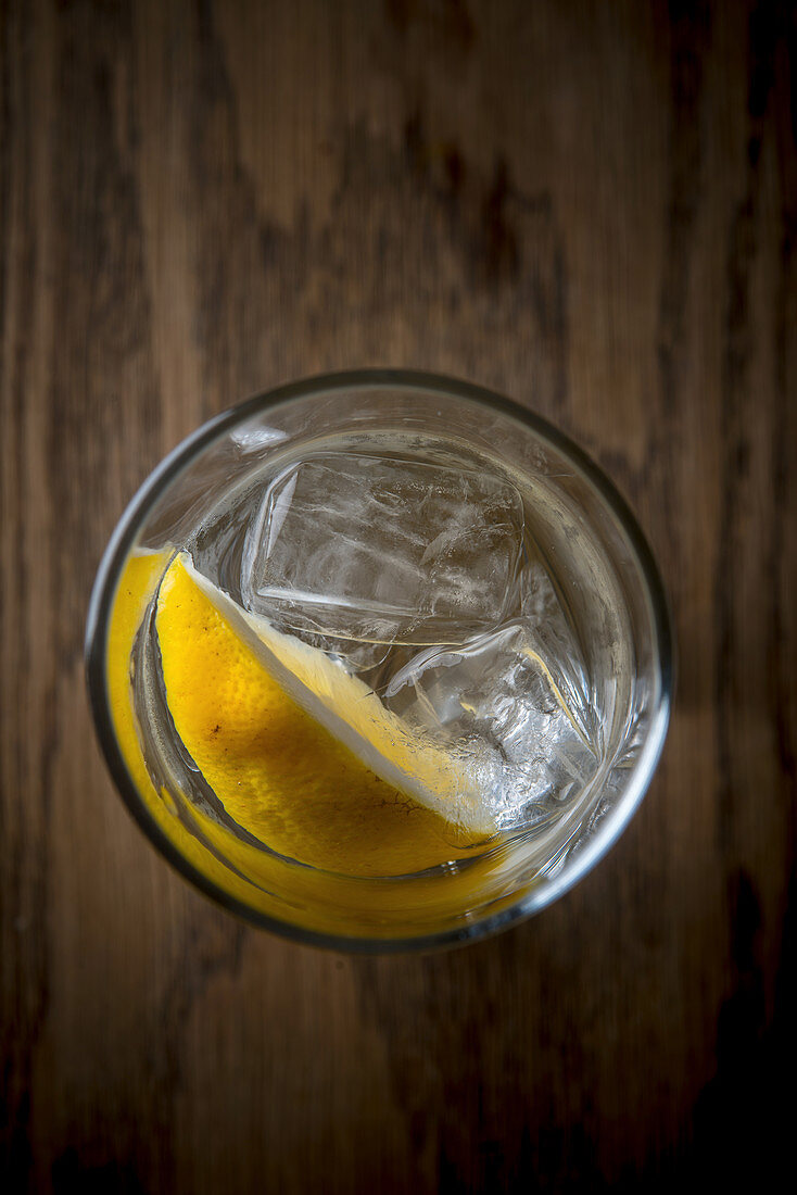 Wasserglas mit Eiswürfeln und Zitronenschnitz