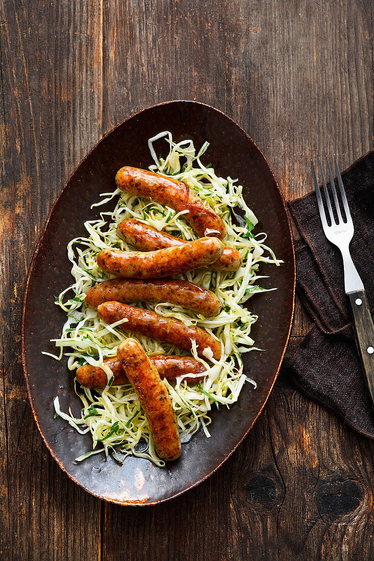 Roast sausages on a white cabbage salad