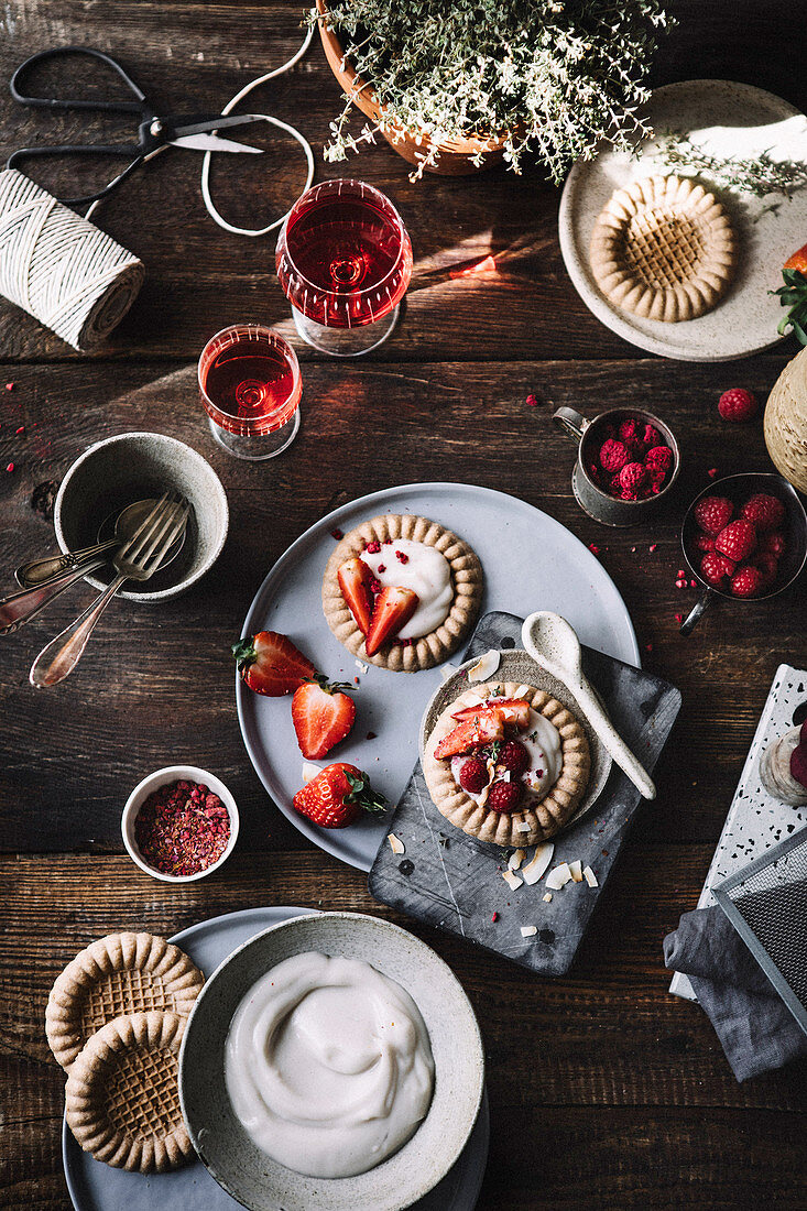 Kekstartelettes mit Vanillepudding und Erdbeeren auf rustikalem Tisch