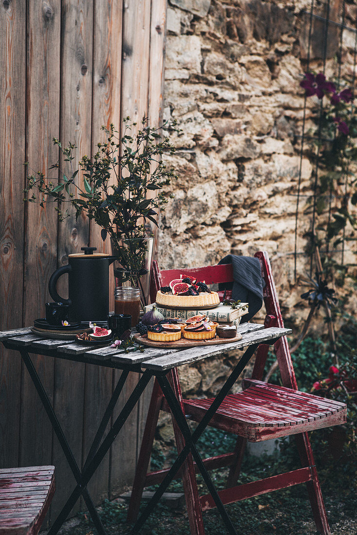 Fig tarts with Chantilly cream and salted caramel on wooden table in garden