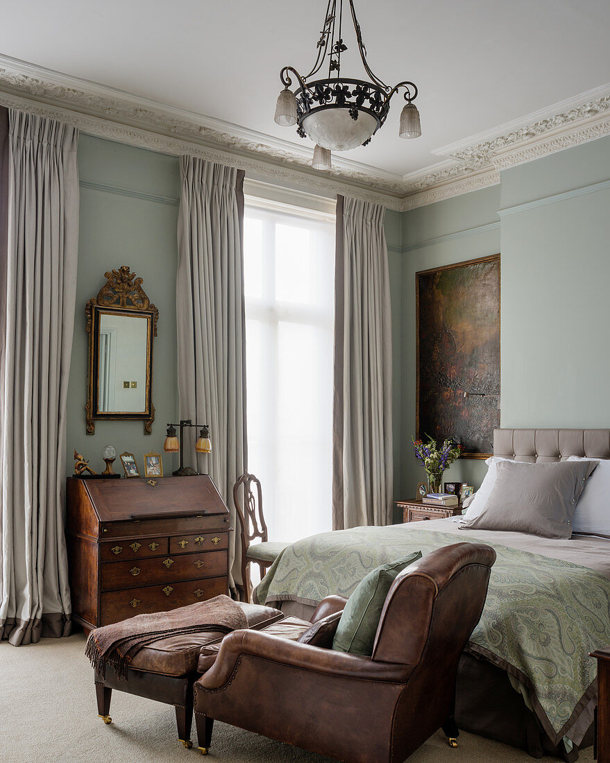 Lederarmsessel in elegantem Schlafzimmer mit hoher Decke und antikem Sekretär