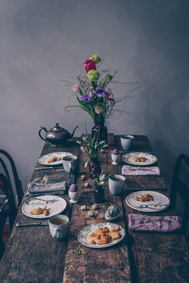 Österlich gedeckter Frühstückstisch mit Tee und Hefe-Osterhasen