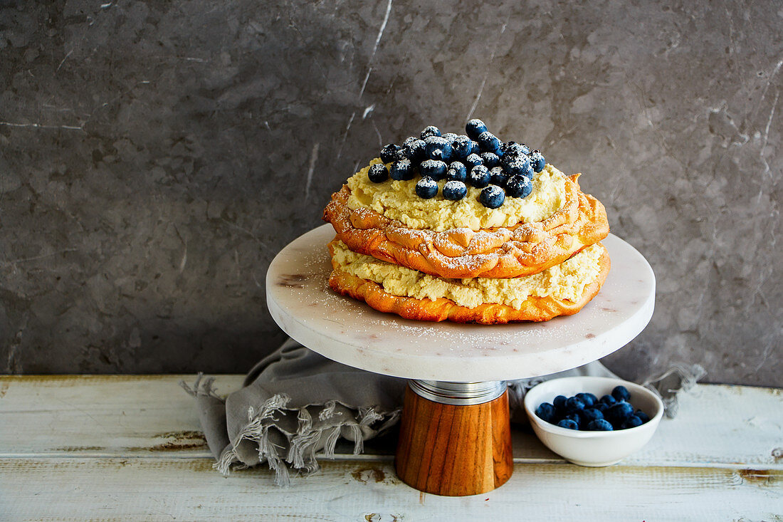 Meringue Pavlova cake on cake stand with blueberry and mascarpone cream