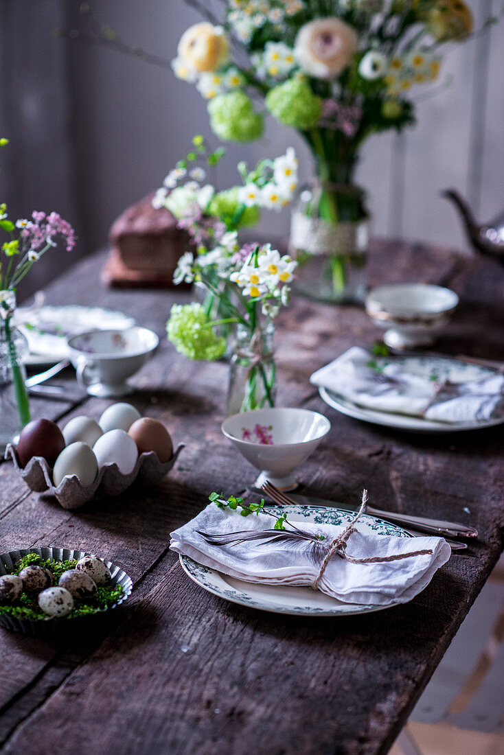 Gedeckter Ostertisch mit Frühlingsblumen und Eiern
