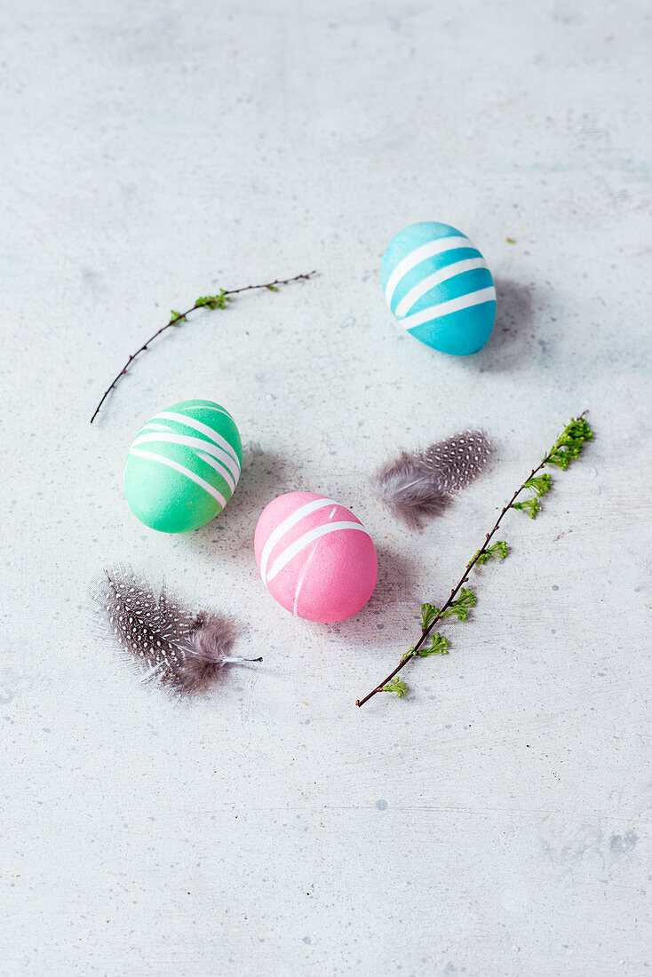 Colourful Easter eggs, spring twigs and quail's feathers