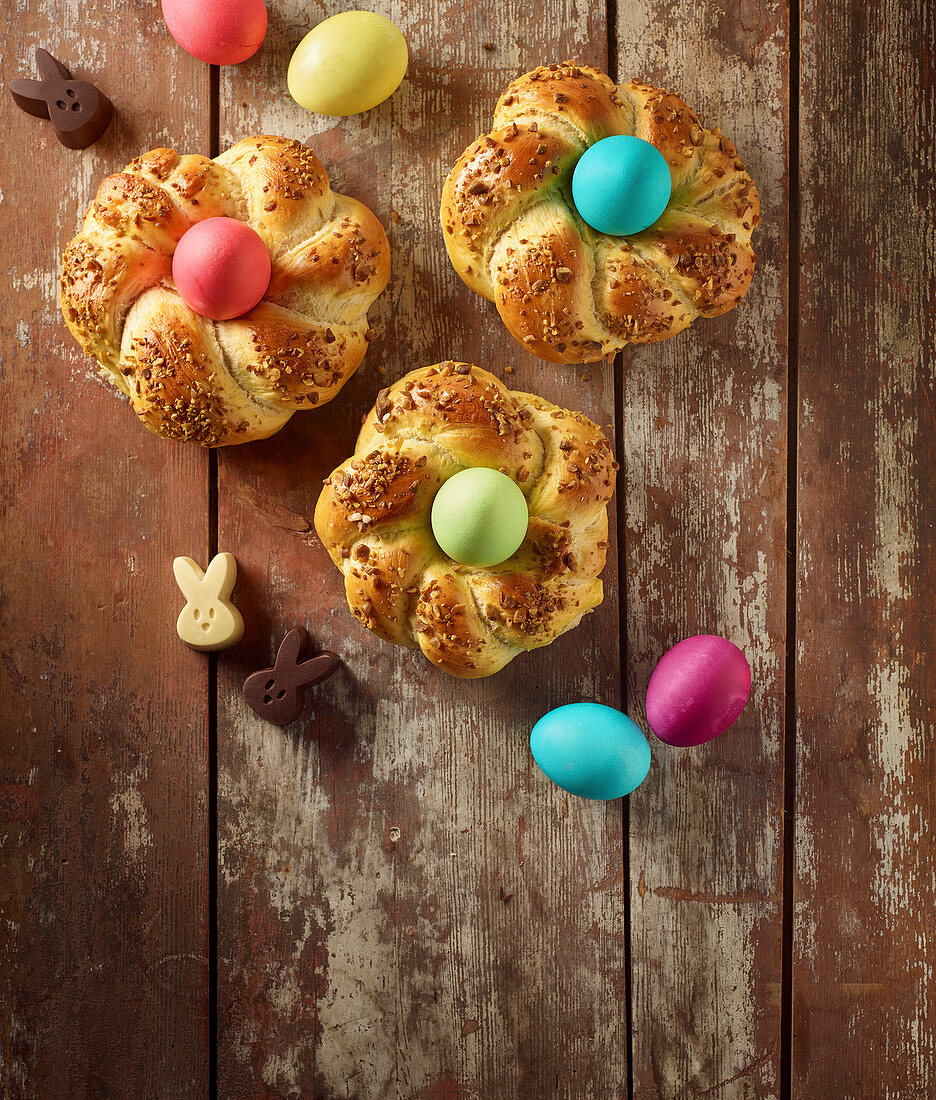 Easter bread nests with colourful Easter eggs on an old brown wooden surface