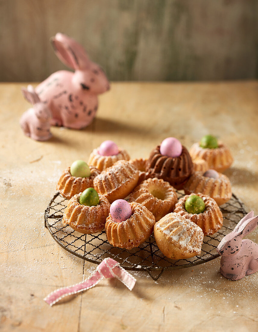 Mini Bundt cakes on a wire rack with dyed quail's eggs and Easter decorations