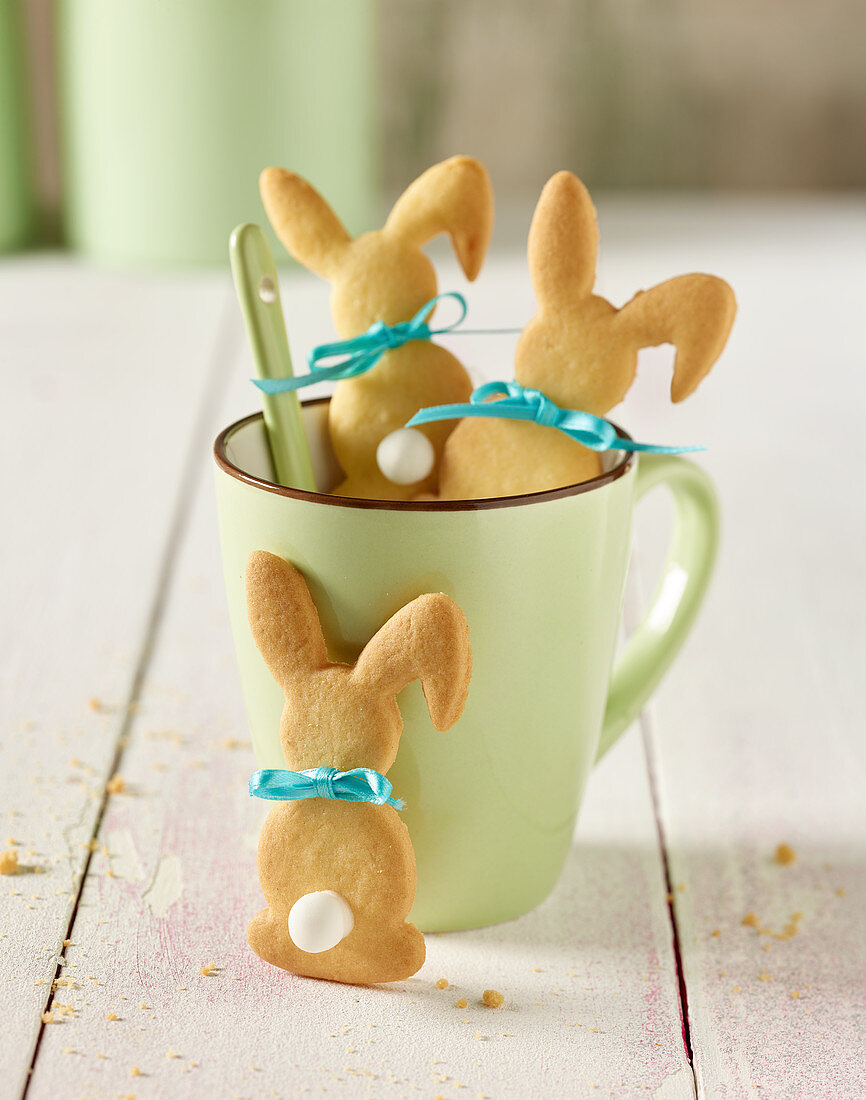 Rabbit-shaped biscuits in a coffee cup on a white wooden table