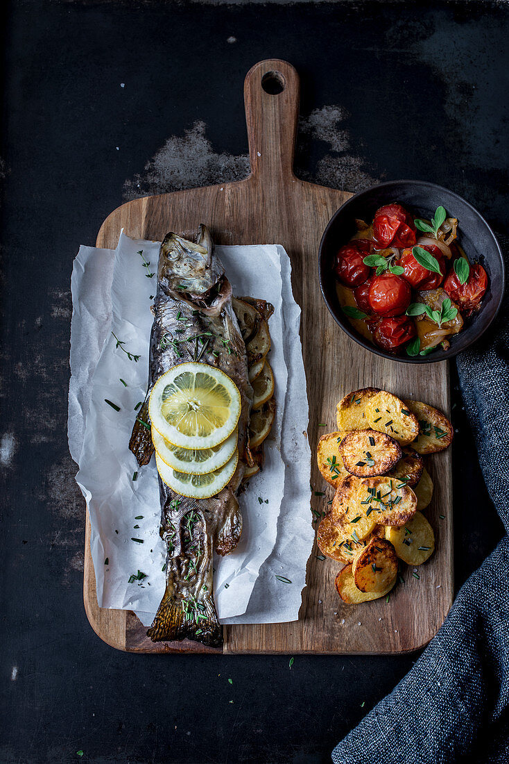 Oven-roasted brook trout with baked potatoes and tomato and onion sauce