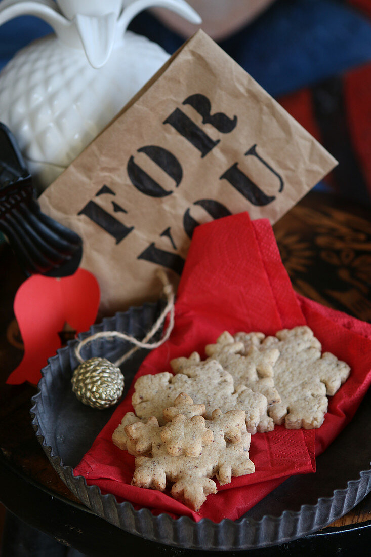 Glutenfreie Schneeflockenplätzchen auf roter Serviette mit Weihnachtsdeko