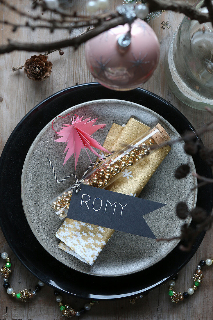 Christmas place setting with golden serviette, name tag and gold beads in test tube