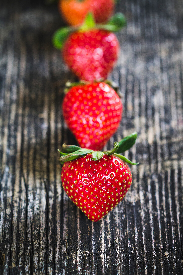 A row of strawberries on a wooden surface