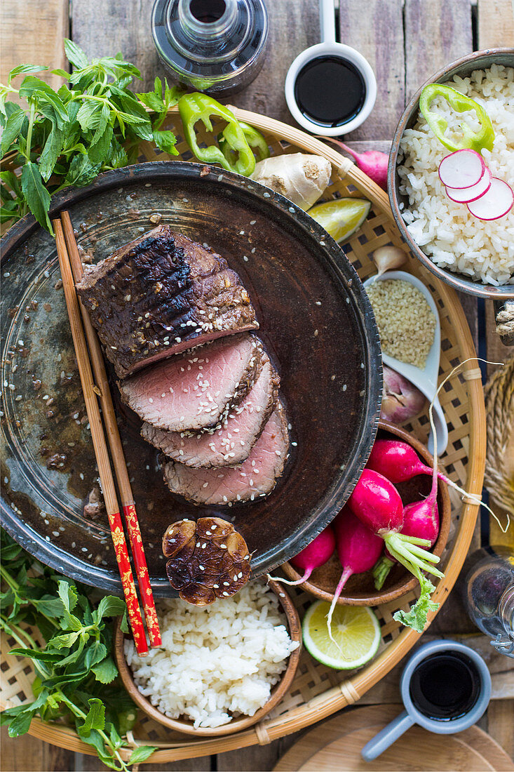 Beef with sesame seeds, rice, radishes and fresh herbs (Asia)