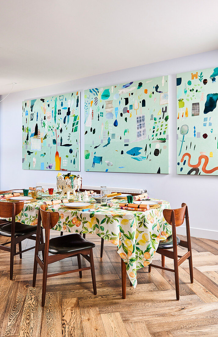 Dreiteiliges abstraktes Wandbild davor gedeckter Esstisch mit mediterraner Tischdecke