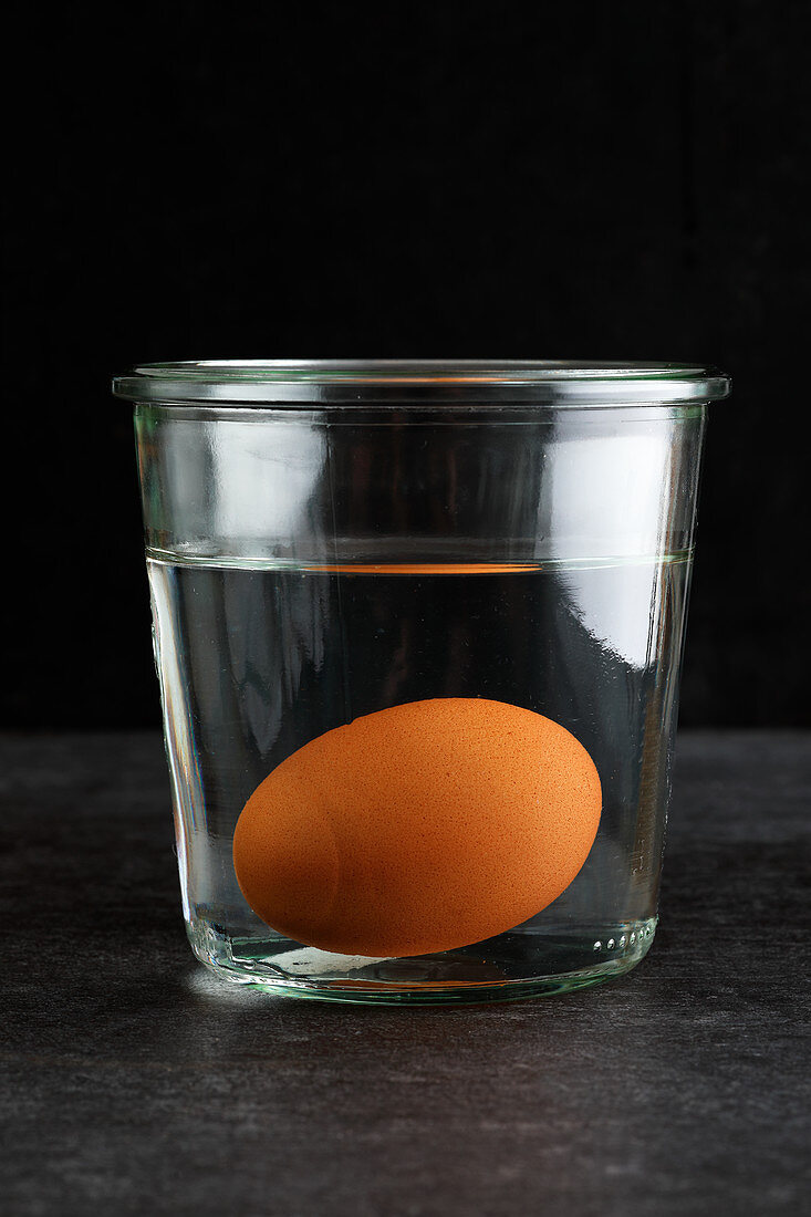 Frische Eier sinken im Wasserglas zu Boden