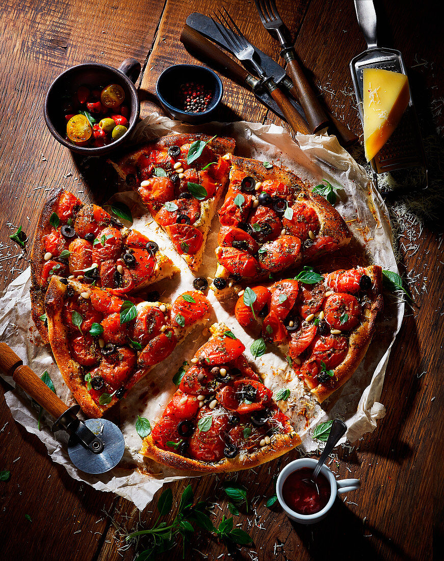 Tomato pizza with olives, sliced on a wooden table