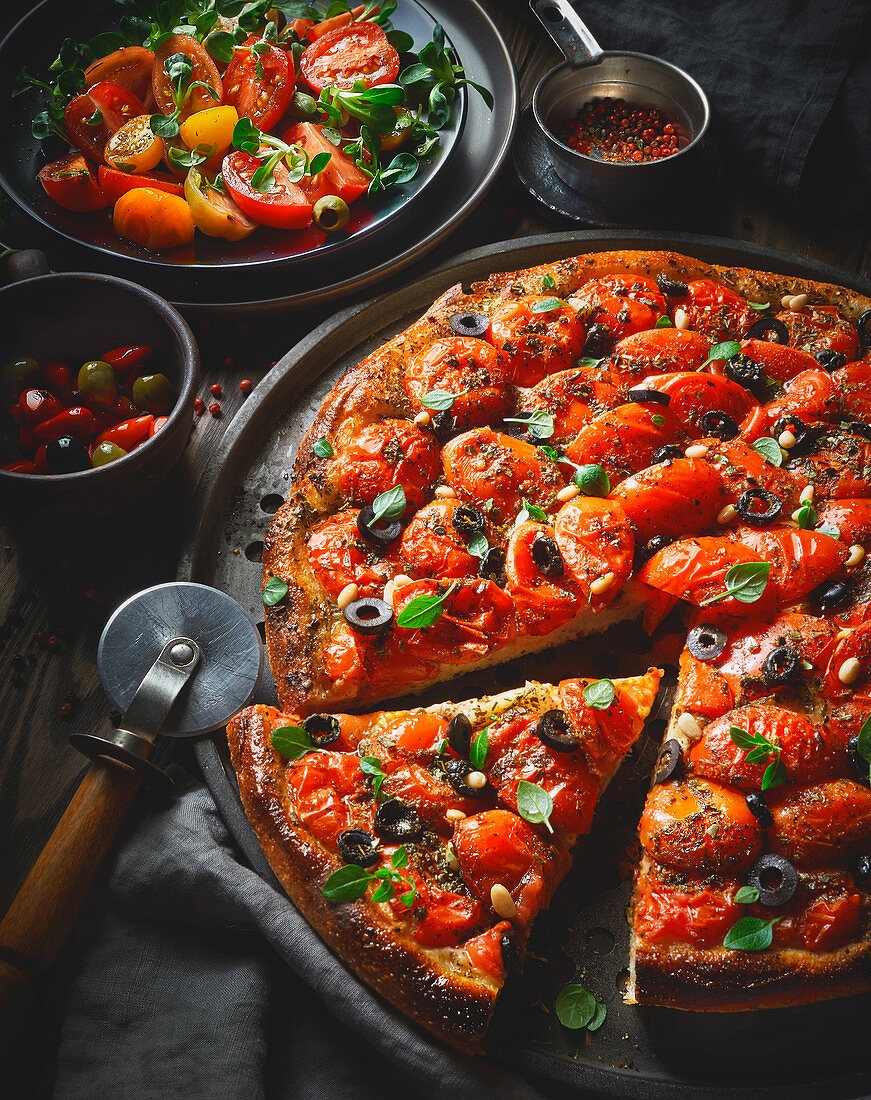 A tomato pizza with olives and pine nuts