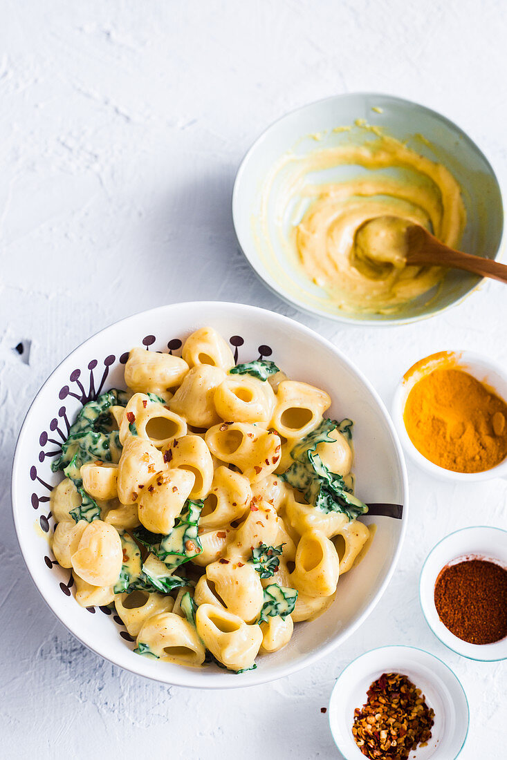 A plate of vegan mac and cheese with kale made with vegan bechamel (soy milk and olive oil), turmeric and paprika powder