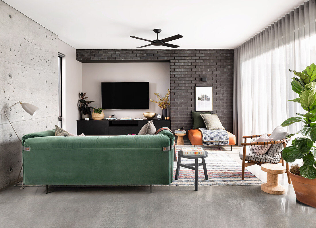 Green velvet sofa in the living room with concrete and brick wall