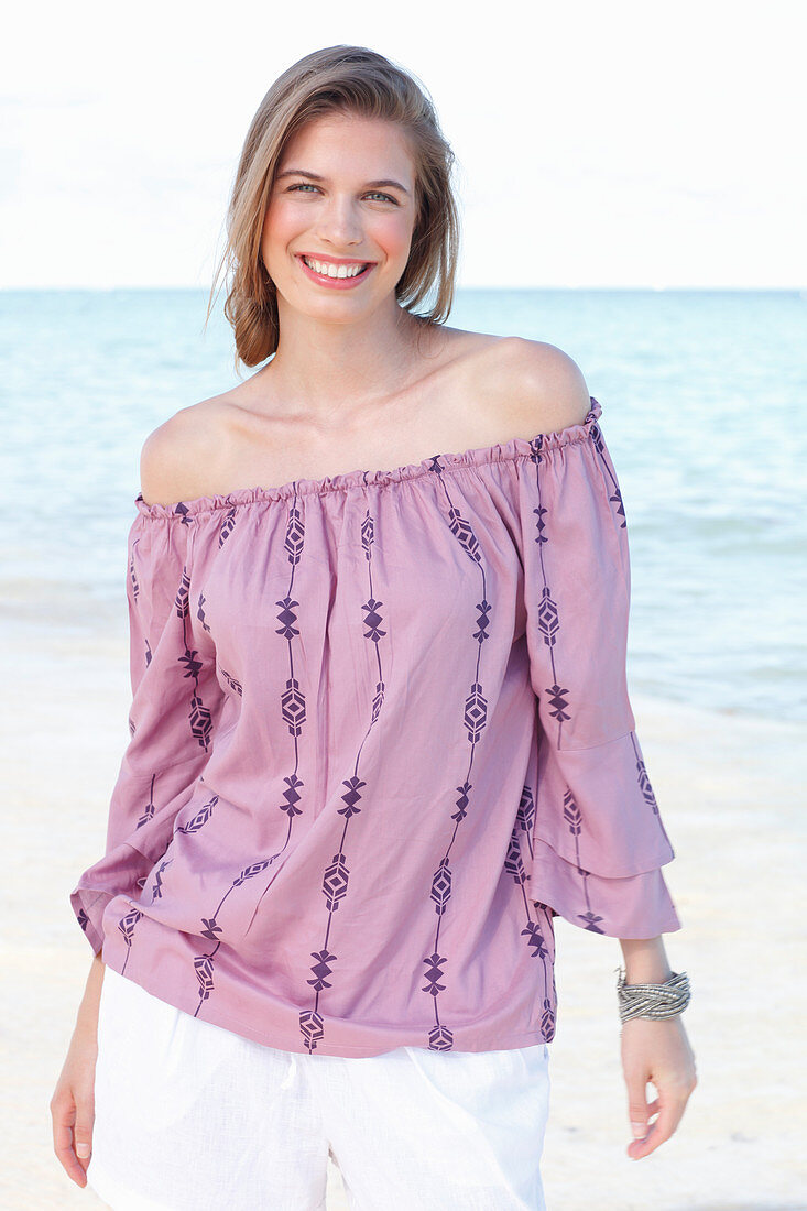 Junge Frau in Carmenbluse und weißen Shorts am Meer